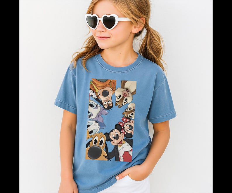 May include: A pale blue t-shirt with a vibrant graphic of cartoon characters such as Mickey Mouse, Goofy, and Chip and Dale. The shirt is made of a soft material, suitable for casual wear.
