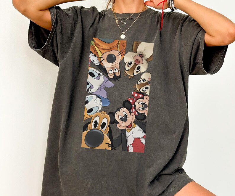 May include: Dark grey oversized t-shirt with a colourful graphic of Disney cartoon characters, including Mickey Mouse, Minnie Mouse, and Pluto. The design is centred on the front of the shirt. The shirt has short sleeves and a relaxed fit.