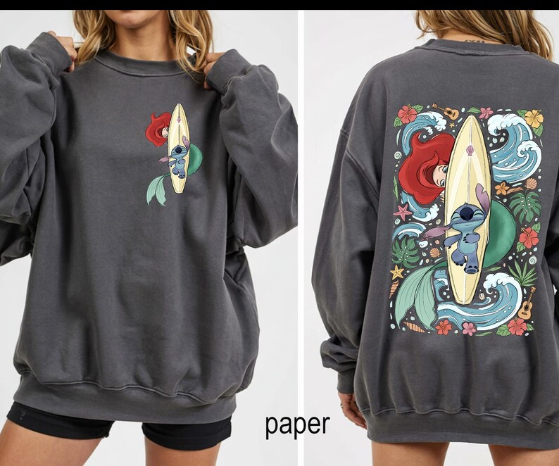 May include: Dark gray sweatshirt featuring a front and back graphic. The front graphic shows Ariel and Stitch on a surfboard. The back graphic shows Ariel, Stitch, waves, flowers, and a ukulele. The word "paper" is printed at the bottom.
