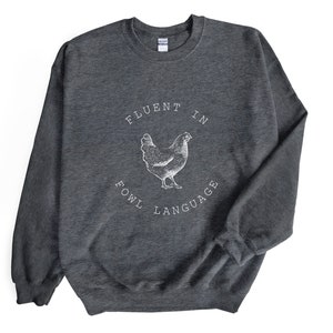 May include: Gray sweatshirt with a white graphic of a chicken and the text "Fluent in Fowl Language".