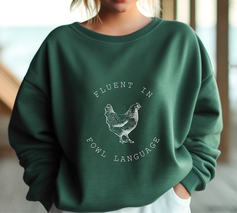 May include: A green sweatshirt with a white graphic of a chicken and the text "Fluent in Fowl Language".