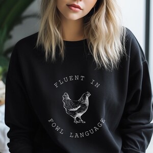 May include: Black sweatshirt with a white graphic of a chicken and the text "Fluent in Fowl Language".
