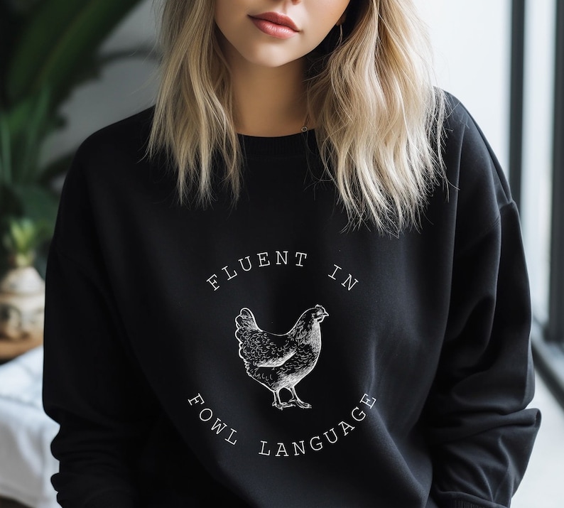 May include: Black sweatshirt with a white graphic of a chicken and the text "Fluent in Fowl Language".