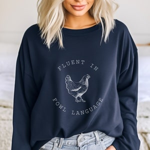 May include: A navy blue sweatshirt with a white graphic of a chicken and the text "Fluent in Fowl Language".