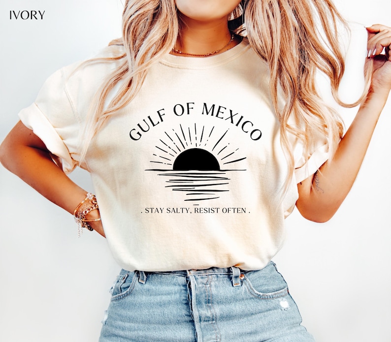 May include: A white t-shirt with a black graphic of a sunset over water with the text "Gulf of Mexico" and ". Stay Salty, Resist Often."