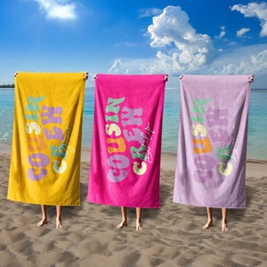 May include: Three beach towels with the text "Cousin Crew" in a retro font. The towels are yellow, pink, and purple.
