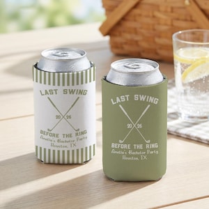 May include: Two can coolers, one white and one olive green, with the text "LAST SWING" and "BEFORE THE RING" printed on them. The coolers have crossed golf clubs and the text "Amelia's Bachelor Party Houston, TX".