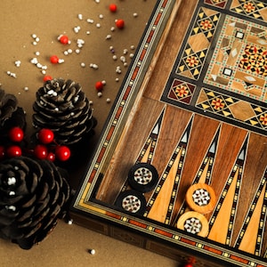 May include: A wooden backgammon board with intricate inlaid designs in shades of brown, black, and white. The board is set up for play with black and white game pieces.