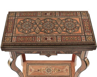 Peut inclure: Une table rectangulaire en bois avec des motifs géométriques complexes incrustés dans diverses nuances de marron, beige et rouge. La table a des pieds incurvés et un dessus détaillé, présentant un aspect mosaïque. La table mesure environ 61 cm de long.