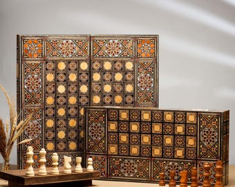 May include: A wooden backgammon and chess board set featuring intricate geometric marquetry in shades of brown, tan, and black. The set includes light-colored wooden chess pieces on a small platform and dark-colored pieces near the board.