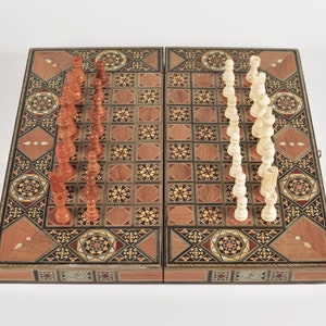 May include: A wooden chessboard with intricate inlaid designs. The board is open and shows a full set of chess pieces, with the white pieces on the right and the brown pieces on the left.