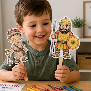 以下が含まれることがあります： 子供が、ダビデとゴリアテのキャラクターを描いた2つの棒人形を持っています。ダビデはパチンコを持ち、ゴリアテは槍と盾を持っています。「DAVID & GOLIATH POPSICLE STICK PUPPETS」の文字が見えます。額入りのプリントには「神と共に、最も小さなものでさえ偉大なことができる！」と書かれています。