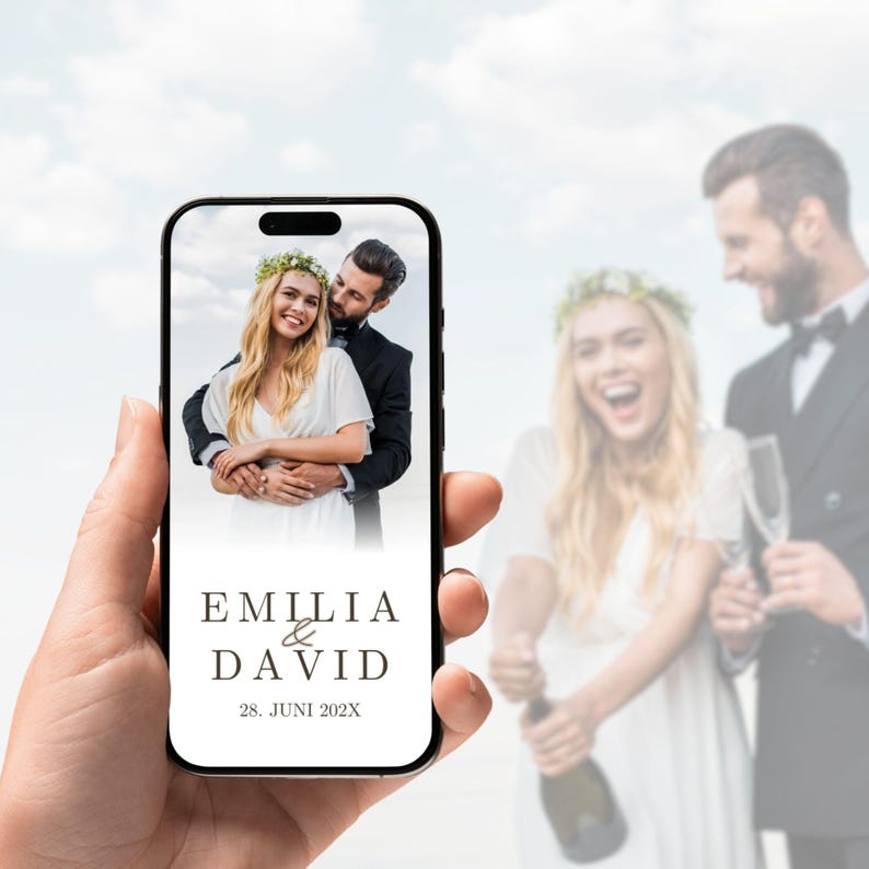 May include: A smartphone screen displaying a wedding photograph of a couple, with the text EMILIA & DAVID and the date 28. JUNI 202X printed below the image in a dark serif font against a clean white background.