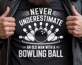May include: A black t-shirt featuring a white graphic of a bowling ball surrounded by pins. The text reads: NEVER UNDERESTIMATE AN OLD MAN WITH A BOWLING BALL. The design is centered on the chest, with bold white lettering and a clean, graphic illustration.