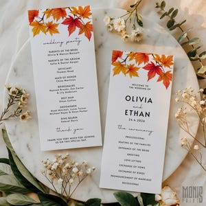 May include: Two white wedding programs with autumn leaf accents. The programs feature text including the names Olivia and Ethan, the date 24.4.2026, and the ceremony details. Floral elements surround the programs.