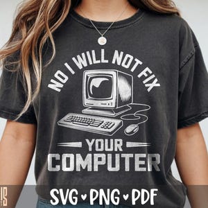 Puede incluir: Una camiseta gris carbón de manga corta con un gráfico blanco de un ordenador antiguo, teclado y ratón. El texto NO I WILL NOT FIX YOUR COMPUTER aparece en una fuente blanca desgastada. La camiseta tiene cuello redondo y un corte holgado.