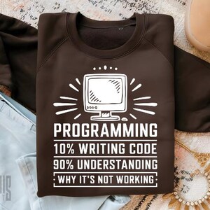 May include: Brown sweatshirt with white text that reads "PROGRAMMING 10% WRITING CODE 90% UNDERSTANDING WHY IT'S NOT WORKING:" and a white outline of a computer monitor.