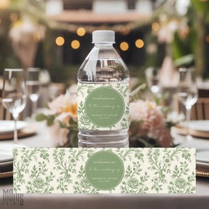 May include: A clear plastic water bottle with a custom label featuring a sage green floral pattern on a cream background. The label includes a circular emblem with the text "welcome to the wedding of MADISON & CONNOR 22.5.2027" in white.