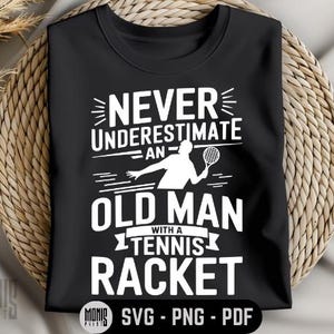 Puede incluir: Camiseta negra con texto blanco que dice "Nunca subestimes a un viejo con una raqueta de tenis". Una silueta blanca de una persona sosteniendo una raqueta de tenis está por encima del texto.