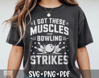 May include: A charcoal gray short-sleeve t-shirt featuring a white distressed graphic print that reads I GOT THESE MUSCLES FROM BOWLING STRIKES with an illustration of a bowling ball hitting pins and small star accents surrounding the design.