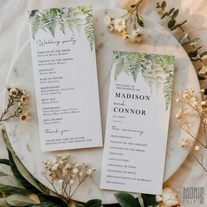 May include: Two white wedding programs with green fern and floral accents. One program lists the wedding party, and the other says "Welcome to the Wedding of Madison and Connor" with the date. The programs are on a marble surface.