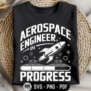 May include: Black t-shirt with white text that reads "Aerospace Engineer in Progress" and a white rocket ship graphic.