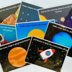 May include: A set of educational cards featuring space-themed illustrations and text prompts. The cards depict planets, astronauts, rockets, and aliens, with phrases such as "Make a buddy for this friendly alien" and "Add flames to help the rocket blast off!"