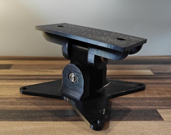 Könnte beinhalten: Eine schwarze, verstellbare Halterung mit strukturierter Oberseite und sternförmiger Basis. Die Halterung hat ein Schwenkdesign und ist mit einer Schraube befestigt. Das Produkt dient zum Halten eines Objekts.