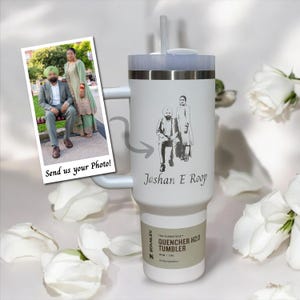 May include: White stainless steel tumbler with a black and white engraved image of a couple. The tumbler has a handle and a straw. The text "Jashan E Roop" is engraved below the image. The text "The Flowstate - Quencher H2.0 Tumbler" is printed on a label on the side of the tumbler.
