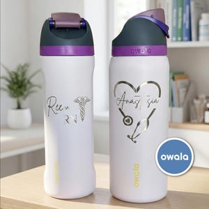 May include: Two white Owala water bottles with purple and gray lids. One bottle has "Ree" and "RN" with a medical symbol. The other has "Anastasia" in a heart with a stethoscope. Both have the Owala logo.