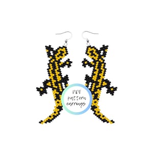 Puede incluir: Un par de pendientes de cuentas con forma de salamandra. Las salamandras son negras y amarillas y están hechas con cuentas de semillas. Los pendientes cuelgan de ganchos de plata para las orejas. La imagen incluye el texto "PDF pattern earrings".