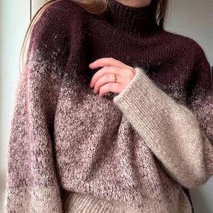 Puede incluir: Un suéter de punto marrón y beige degradado con cuello alto.