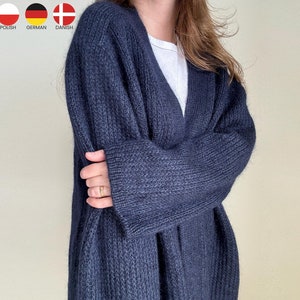 Op de afbeelding: Een donkerblauwe gebreide cardigan met een lange, open voorkant en lange mouwen. De cardigan is gemaakt van een zacht, pluche materiaal.