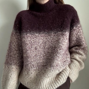 Peut inclure: Un pull surdimensionné dans un dégradé de couleurs, passant d'un bordeaux profond au col roulé à un beige clair à l'ourlet. Le tricot présente un ourlet et des poignets côtelés, offrant un look confortable et élégant.