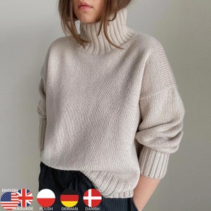 May include: A cream-colored turtleneck sweater with a ribbed knit texture. The sweater has long sleeves and a relaxed fit.