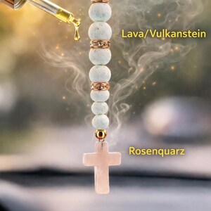 Könnte beinhalten: Ein Auto-Charm mit hellblauen Lavasteinperlen, goldfarbenen Abstandshaltern und einem rosa Rosenquarz-Kreuz. Der Charm hat ein herzförmiges Etikett mit der Aufschrift "Hand Made With Love".