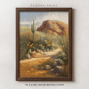 May include: A framed landscape painting of a desert scene. The artwork depicts a path leading towards a reddish-brown mountain, with cacti and other desert plants in the foreground. The painting is in a dark brown wooden frame. The text "YUNORA PRINT" and "7K ULTRA HIGH-RESOLUTION" are visible.