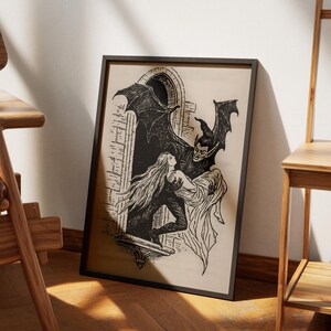 May include: Black and white framed print depicting a gothic scene. A winged demon figure embraces a woman in a window. The artwork features detailed linework and a vintage aesthetic, perfect for Halloween or gothic decor.