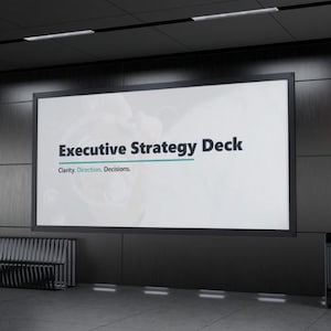May include: A large, rectangular display screen with the text "Executive Strategy Deck" in black and teal. Below, the text reads "Clarity. Direction. Decisions." The screen is set against a dark gray wall.