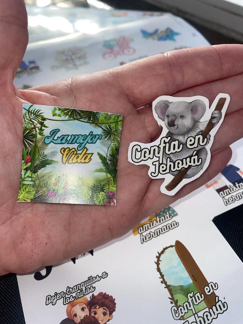 May include: A set of colorful stickers with inspirational messages in Spanish. The stickers feature a koala, a jungle scene, and the phrases "La Mejor Vida" and "Confia en Jehova".
