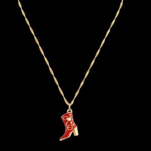 Op de afbeelding: Een goudkleurige ketting met een rode en gouden cowboylaars hanger. De laars heeft een gouden hak en is versierd met gouden krullen en een kleine heldere edelsteen. De ketting heeft een gedraaid touwontwerp.