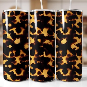 Puede incluir: Tres vasos de acero inoxidable con un diseño de caparazón de tortuga. El diseño presenta una mezcla de manchas marrón oscuro y amarillo dorado, creando un aspecto natural y texturizado. Cada vaso tiene una pajita blanca.