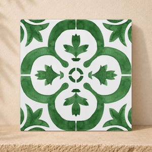 Pode incluir: Um azulejo de cerâmica quadrado com fundo branco e um padrão botânico verde simétrico e repetitivo. O design consiste em quatro linhas curvas interligadas que formam um motivo floral central com folhas pontiagudas em cada canto.