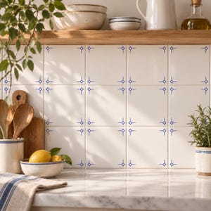 May include: A kitchen backsplash featuring square white ceramic tiles with a repeating blue star-shaped pattern at each corner intersection. The tiles are arranged in a grid pattern, creating a clean and uniform look for the wall surface.