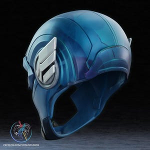 K&ouml;nnte beinhalten: Ein blauer und silberner Helm mit einem Fl&uuml;geldesign an der Seite. Der Helm besteht aus hartem Kunststoff und hat eine glatte, gl&auml;nzende Oberfl&auml;che.
