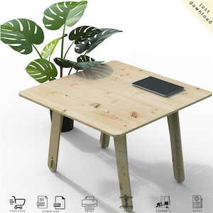 Puede incluir: Una mesa cuadrada de madera clara con patas anguladas. Una tableta negra descansa sobre la mesa. Una planta en maceta con hojas verdes grandes está al lado de la mesa. Las palabras "just download" están en la esquina superior derecha.