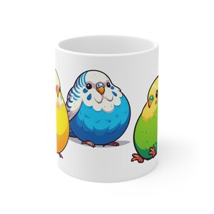 Puede incluir: Taza de cerámica blanca con un diseño de tres periquitos de dibujos animados en amarillo, azul y verde. Los pájaros tienen cuerpos grandes y redondos y están colocados en la superficie de la taza. El diseño es una ilustración colorida y caprichosa.