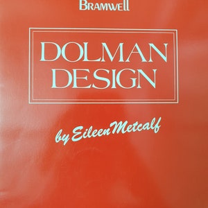 May include: A red cover with the text "BRAMWELL" at the top. The words "DOLMAN DESIGN" are in a rectangular box, and "by Eileen Metcalf" is written below. The text is in a light blue colour.