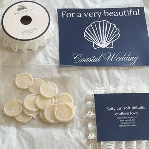 K&ouml;nnte beinhalten: Eine Auswahl an Hochzeitsartikeln, darunter wei&szlig;e Spitzenborte, marineblaue Karten mit Muscheldesign und Wachssiegel. Der Text "Pack an order with me" und "Coastal Wedding" sind ebenfalls zu sehen.