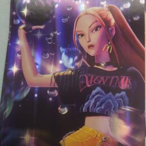 May include: A rectangular trading card featuring a stylized illustration of a person with long hair, wearing a black crop top with text, yellow pants, and a McDonald's logo earring. The card has a holographic finish, floating bubbles, and the text HELLO FRIEND.